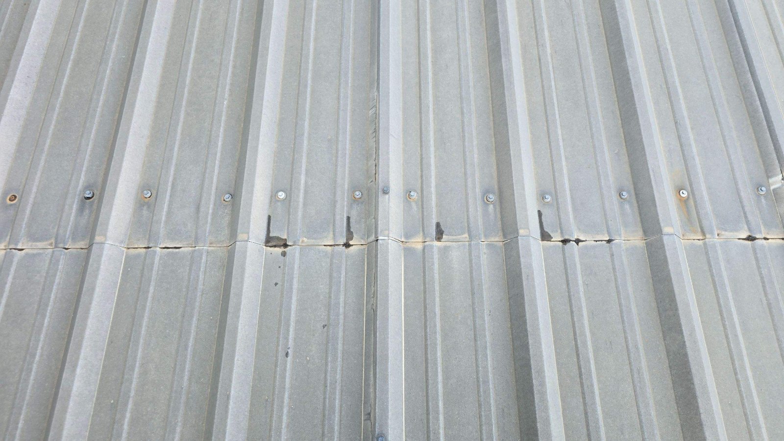 Black mastic smeared over metal roof panel laps